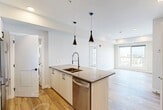Located at 8450 106A Avenue NW in Edmonton, Alberta, this thoughtfully designed 2-bedroom, 2-bathroom unit offers a modern open-concept layout with clean lines and contemporary finishes throughout. Light-toned hardwood-style flooring flows seamlessly across the main living areas, complementing the crisp white walls and recessed lighting that create a bright, welcoming atmosphere.

The kitchen is a standout feature, boasting an extended island with a dark quartz countertop, an undermount sink with a pull-down faucet, and sleek pendant lighting. White cabinetry with matte black hardware pairs with a dark tile backsplash and a full suite of stainless steel appliances, including a built-in microwave, range, and dishwasher.

The living area is bathed in natural light from large windows offering open city views. The primary bedroom includes a walk-in closet with wire shelving, while the second bedroom also features generous closet storage. Both bedrooms connect to well-appointed bathrooms — one featuring a vessel sink, glass-enclosed shower with tile surround, and a window for natural light; the other showcasing a soaker tub with floor-to-ceiling tile. A dedicated in-suite laundry room with stacked washer and dryer adds everyday convenience to this well-planned urban residence.