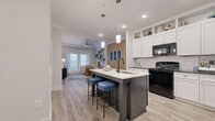 Located in Mebane, NC, this efficiently designed one-bedroom, two-bathroom residence makes excellent use of its single-floor layout. The open-concept kitchen and living area serves as the heart of the home, anchored by a striking island with a light stone countertop, dark cabinetry, an undermount sink with a matte black faucet, and pendant lighting overhead. White shaker-style cabinets line the walls, complemented by a classic subway tile backsplash, black appliances including a gas range and French door refrigerator, and a built-in wine rack — delivering both style and functionality. Wood-look plank flooring runs throughout the main living areas, adding warmth and continuity. The living room is bright and inviting, featuring a ceiling fan, French doors that invite natural light, and a distinctive wood slat accent wall. The generously sized primary bedroom offers dedicated closet space and comfortable proportions. Both bathrooms are well-appointed, with white vanity cabinetry, dark countertops, and a soaking tub with matte black fixtures in the full bath. The overall ambiance is clean, modern, and cohesive — ideal for comfortable everyday living.
