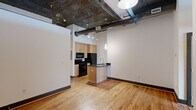 Located at 132 North Sycamore Street in Petersburg, VA, this two-bedroom, two-bathroom loft-style residence showcases a distinctive industrial aesthetic throughout its single-floor layout. The open living area immediately impresses with its ornate embossed tin ceilings, exposed metal ductwork, and warm hardwood flooring that runs continuously through the main living spaces, creating a cohesive urban loft atmosphere.

The kitchen is thoughtfully designed with light maple cabinetry, dark granite countertops, black appliances including a range, microwave, and refrigerator, and a peninsula with a stainless steel sink that opens to the living area — ideal for both cooking and entertaining. Pendant lighting accents the space with a modern industrial touch.

The spacious primary bedroom offers ample room and features dual closets with light wood doors, while the second bedroom is well-proportioned with a ceiling fan and access to natural light. Both bedrooms continue the hardwood flooring found throughout the home.

The two bathrooms are finished with tile flooring and wood-toned cabinetry with dark countertops. One bathroom features a full tub-shower combination, while the other provides a more compact, functional layout. Together, these spaces reflect a clean, modern finish consistent with the overall design of the home.