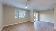 This single-floor residence offers a thoughtfully designed layout that balances comfort and functionality. The open living area is finished with light wood-look flooring, crown molding, and neutral toned walls. A ceiling fan provides year-round comfort, while a large window fitted with horizontal blinds fills the room with natural light. A sliding glass door leads directly to an outdoor area, creating a seamless indoor-outdoor connection. The kitchen is a standout feature, showcasing gray shaker-style cabinetry, crisp white quartz countertops, and a classic subway tile backsplash. Stainless steel appliances include a gas range, built-in microwave, and refrigerator, complemented by a wall-mounted range hood. The bedrooms are carpeted for warmth and comfort, each with a ceiling fan and window offering natural light. A spacious walk-in closet with wire shelving and hanging rods provides generous storage. The bathroom includes a full tub and shower combo with chrome fixtures and wood-look flooring. A dedicated laundry room houses a full-size washer and dryer. The attached garage features an automatic opener and offers additional storage potential, completing this practical and well-equipped residence.