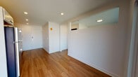 This single-floor unit features a clean, contemporary design throughout, with warm hardwood-style flooring and crisp white walls creating a bright, cohesive atmosphere. Recessed lighting is installed throughout, ensuring consistent illumination across all areas.

The kitchen is well-appointed with stainless steel appliances, including a range, microwave, refrigerator, and dishwasher. White cabinetry lines the upper and lower walls, complemented by a dark tile backsplash that adds visual contrast. Countertops provide ample workspace, and the layout maximizes efficiency within the galley-style configuration.

The open living area flows naturally from the kitchen, offering a generous, flexible space filled with natural light from a sliding glass door that leads to a private balcony. The balcony provides views of the surrounding urban landscape. The entry area features a dedicated foyer with a solid front door, offering a clear separation from the main living space.

The bathroom includes a full bathtub with shower, a white vanity with storage, and a toilet. Notably, an in-unit stacked washer and dryer is conveniently located within the bathroom area, adding practical functionality. A closet with shelving is also present, providing dedicated storage space.