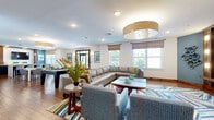 Located at 556 Colonial Rd in Franklin Lakes, New Jersey, this thoughtfully designed single-floor space offers a seamless blend of comfort and modern functionality. Rich hardwood flooring runs throughout, tying together each distinct area with warmth and visual continuity.

The expansive living room serves as the heart of the space, furnished with a generous sectional sofa and accent chairs arranged around a central coffee table. A bold, colorful area rug anchors the seating arrangement, while large windows dressed in neutral Roman shades invite abundant natural light and views of the lush greenery outside. A wall-mounted flat-screen TV with flanking accent lighting and decorative wall art adds a polished, curated feel to the room.

The kitchen is a standout feature, boasting dark navy cabinetry, a striking mosaic tile backsplash, stainless steel appliances, and crisp white countertops. A central island with modern pendant lighting and contemporary seating provides an ideal gathering spot. An adjacent built-in counter with dark cabinetry and a mounted TV extends the kitchen's utility and style.

The private office is bright and clean, featuring a sleek white desk with acrylic chairs, a cozy window seat, and a fireplace — creating a productive yet comfortable work environment.

A welcoming entryway with glass double doors and vibrant artwork completes this well-appointed space.