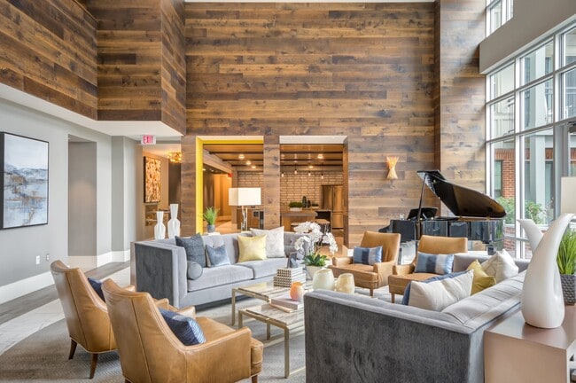 Acogedor salón para residentes con lujosos asientos, un piano de cola y un ambiente cálido y moderno. - The Heights at Goose Creek Village
