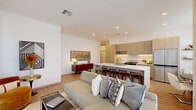 This well-appointed 2-bedroom, 1-bathroom residence offers a thoughtfully designed single-level layout with a clean, contemporary aesthetic. The open-concept living and kitchen area serves as the heart of the home, where light wood-tone cabinetry, a large center island with a white quartz countertop and built-in seating, and stainless steel appliances create a sleek, functional space. Under-cabinet lighting and recessed ceiling lights enhance the bright, airy atmosphere. The living area extends naturally from the kitchen, anchored by large floor-to-ceiling windows with roller shades that invite abundant natural light and outdoor views. Light hardwood flooring runs throughout, lending warmth and continuity across the entire space. The primary bedroom features a dedicated walk-in closet and connects to the shared hallway, while the secondary bedroom is brightened by generous windows dressed with linen drapes. The full bathroom is finished with white grid tile, a soaking tub, glass-enclosed shower, warm brass fixtures, wood-framed mirrors, and a floating vanity with a white countertop, striking a refined balance between modern and warm design sensibilities. A dedicated closet provides additional storage. Overall, the space exudes a calm, modern ambiance with cohesive finishes throughout.
