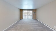 Located at 100 S Village Blvd in Baldwinsville, NY, this two-bedroom, two-bathroom residence offers a practical and comfortable single-floor layout. The kitchen is well-appointed with warm maple cabinetry, granite-style countertops, light wood-look tile flooring, and black appliances including a gas range, built-in microwave, dishwasher, and a double-basin sink — providing ample storage and workspace for everyday cooking. The open living room features plush carpeting and a sliding glass door that leads to a private balcony, allowing for natural light and outdoor views. Both bedrooms are carpeted and finished with neutral warm-beige walls and baseboard heating. The primary bedroom offers a generous footprint with a closet, while the second bedroom includes a double closet with paneled doors and a window overlooking the outdoors. A hallway connects the main living areas efficiently. The two bathrooms include one with a full tub/shower combo with chrome fixtures, and a second with a glass-door walk-in shower. Throughout the residence, a consistent neutral color palette and clean finishes create a cohesive, move-in-ready atmosphere suited for comfortable everyday living.