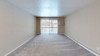 Located at 100 S Village Blvd in Baldwinsville, NY, this two-bedroom, two-bathroom residence offers a practical and comfortable single-floor layout. The kitchen is well-appointed with warm maple cabinetry, granite-style countertops, light wood-look tile flooring, and black appliances including a gas range, built-in microwave, dishwasher, and a double-basin sink — providing ample storage and workspace for everyday cooking. The open living room features plush carpeting and a sliding glass door that leads to a private balcony, allowing for natural light and outdoor views. Both bedrooms are carpeted and finished with neutral warm-beige walls and baseboard heating. The primary bedroom offers a generous footprint with a closet, while the second bedroom includes a double closet with paneled doors and a window overlooking the outdoors. A hallway connects the main living areas efficiently. The two bathrooms include one with a full tub/shower combo with chrome fixtures, and a second with a glass-door walk-in shower. Throughout the residence, a consistent neutral color palette and clean finishes create a cohesive, move-in-ready atmosphere suited for comfortable everyday living.