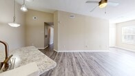 Located at 2603 Silkwood Circle in Orlando, Florida, this single-story, three-bedroom, two-bathroom home offers a well-designed layout with comfortable living spaces throughout. The open-concept living, dining, and kitchen area serves as the heart of the home, featuring wood-look laminate flooring, neutral warm-toned walls, and ceiling fans that enhance airflow and comfort. Natural light filters in through windows, creating a bright and welcoming ambiance.

The kitchen is a standout feature, boasting white shaker cabinetry, granite-style countertops, a tiled backsplash, and a full suite of stainless steel appliances including a refrigerator, range, and microwave. A central kitchen island with a built-in sink and pendant lighting above adds both style and functionality, making it ideal for cooking and casual dining.

The three bedrooms are carpeted for comfort, with the spacious primary bedroom offering a generous walk-in closet equipped with wire shelving. Additional bedrooms include louvered bifold closets. Both bathrooms feature white vanities with granite-style countertops, wood-look flooring, and clean, classic finishes. A dedicated laundry room houses a full-size washer and dryer. Five closets throughout the home provide ample storage.