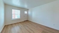 This 690 square foot apartment in Oklahoma City offers a practical and efficient living space. The layout comprises two bedrooms, one bathroom, a kitchen, and a combined living room area, all on a single floor. The primary bedroom is notably spacious at 150 square feet, providing a comfortable retreat.

The interior boasts a modern aesthetic with clean lines and neutral tones. Light-colored walls and ceiling create an airy atmosphere, complemented by the warmth of wood-look flooring throughout most of the living areas. Large windows in the bedrooms and living space allow for ample natural light, enhancing the open feel of the apartment.

The kitchen features contemporary white cabinetry, contrasting nicely with stainless steel appliances, including a refrigerator, oven, and over-the-range microwave. The bathroom is equipped with a combination tub-shower unit, a single vanity, and convenient built-in storage.

Ceiling fans in the bedrooms provide additional comfort, while carpeting in these areas adds a cozy touch. The apartment also includes a hallway and closet space for storage. Overall, this compact yet well-designed apartment offers a balanced blend of functionality and modern style, suitable for individuals or small families seeking an efficient living space in Oklahoma City.