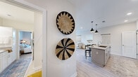 Located at 7301 Topwater Dr in Wilmington, NC, this single-floor, 2-bedroom, 2-bathroom home offers a thoughtfully designed layout with modern finishes throughout. Light hardwood-style flooring flows seamlessly across the open-concept living areas, complemented by neutral walls that enhance the bright, airy atmosphere.

The kitchen serves as a central hub, featuring white shaker cabinetry, quartz countertops, a herringbone tile backsplash, stainless steel appliances, and a large island with seating beneath stylish matte black pendant lights. The adjacent living room is warm and welcoming, offering a comfortable, relaxed setting with natural light filtering through nearby windows.

Both bedrooms are well-sized and fitted with ceiling fans, large windows that invite natural light and outdoor views, and generous closet space. The primary bedroom includes a walk-in closet with built-in shelving and hanging rods. The two bathrooms are cleanly finished with white cabinetry, quartz countertops, subway tile surrounds, and wood-framed mirrors. The primary bath conveniently connects to an in-unit laundry area with a stacked washer and dryer.

A dedicated entry hallway decorated with woven wall art adds character and guides you into the home's cohesive, coastal-inspired design.
