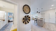 Located at 7301 Topwater Dr in Wilmington, NC, this single-floor, 2-bedroom, 2-bathroom home offers a thoughtfully designed layout with modern finishes throughout. Light hardwood-style flooring flows seamlessly across the open-concept living areas, complemented by neutral walls that enhance the bright, airy atmosphere.

The kitchen serves as a central hub, featuring white shaker cabinetry, quartz countertops, a herringbone tile backsplash, stainless steel appliances, and a large island with seating beneath stylish matte black pendant lights. The adjacent living room is warm and welcoming, offering a comfortable, relaxed setting with natural light filtering through nearby windows.

Both bedrooms are well-sized and fitted with ceiling fans, large windows that invite natural light and outdoor views, and generous closet space. The primary bedroom includes a walk-in closet with built-in shelving and hanging rods. The two bathrooms are cleanly finished with white cabinetry, quartz countertops, subway tile surrounds, and wood-framed mirrors. The primary bath conveniently connects to an in-unit laundry area with a stacked washer and dryer.

A dedicated entry hallway decorated with woven wall art adds character and guides you into the home's cohesive, coastal-inspired design.