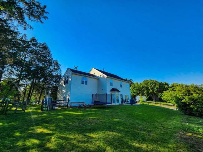 Rear view showing large yard, trees, and space for outdoor fun. - 7801 Peach Blossom Ct