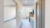 Located at 1216 N Superior St in Spokane, Washington, this efficiently designed studio unit offers a thoughtfully organized single-floor layout. Light wood laminate flooring runs throughout the entire space, creating a cohesive and clean aesthetic. The open main area features crisp white walls, recessed lighting, exposed ceiling beams, and dark baseboards that provide a subtle contrast to the neutral palette. Natural light filters in through multiple windows, offering views of the surrounding neighborhood.

The kitchen is well-appointed with sage green shaker-style cabinetry on both upper and lower levels, a stainless steel sink with a modern gooseneck faucet, a full-size stainless steel refrigerator, and a built-in microwave. The light countertops complement the cabinetry, keeping the space feeling bright and functional.

The bathroom maintains the same clean, contemporary design with a vessel sink atop a gray vanity cabinet, a framed mirror with overhead lighting, and a shower/tub combination. The consistent use of gray tones and light wood flooring ties the bathroom seamlessly into the overall design language of the unit. A baseboard heating system is present throughout, ensuring year-round comfort in this efficiently planned Spokane residence.