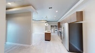 This thoughtfully designed single-floor residence offers two bedrooms and two bathrooms within a well-appointed, contemporary floor plan. The open-concept kitchen serves as the heart of the home, featuring a central island with a sink, warm wood-toned cabinetry extending to the ceiling, stainless steel appliances including a side-by-side refrigerator, electric range, and built-in microwave, all set against light-toned tile flooring. A stylish globe pendant light anchors the kitchen island, adding a modern touch. The layout flows seamlessly into the living area, which features a tray ceiling, ceiling fan, recessed lighting, and sliding glass doors that open to a private balcony with outdoor views. The primary bedroom is generously sized, benefiting from natural light through a large window, a ceiling fan, and dedicated closet space. The second bedroom also receives ample natural light and offers a bright, versatile space. The primary bathroom impresses with large-format marble-style tile in the glass-enclosed walk-in shower, wood-toned vanity cabinetry, and elegant brushed nickel fixtures. The second bathroom features a full soaking tub with a tiled surround. A dedicated in-unit laundry room with a full-size washer and dryer completes this well-equipped residence.