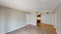 Located at 4465 E 31st St in Tulsa, Oklahoma, this one-bedroom, one-bathroom unit offers a practical and well-organized single-floor layout. The living room serves as the heart of the space, featuring light wood-look laminate flooring, neutral gray walls, a textured ceiling, and a ceiling fan that provides both comfort and airflow. French doors bring in natural light and offer a view to the outside, enhancing the openness of the room. The kitchen is efficiently designed with warm wood cabinetry, a countertop sink, and ample storage, flowing naturally from the main living area. A hallway connects the living spaces to the private areas of the unit. The bedroom is a comfortable retreat finished with soft wall-to-wall carpet, neutral toned walls, a textured ceiling, and a window fitted with blinds that allows natural light while maintaining privacy. The bathroom is clean and functional, featuring a vanity with a white countertop, a mirrored wall, wood-toned cabinetry, and a shower-tub combination. Throughout the unit, a consistent neutral color palette and practical finishes create a calm, cohesive atmosphere suited for comfortable everyday living.