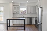 Located at 1630 S Delaware St, Unit 216 in San Mateo, CA, this single-level residence offers a clean, contemporary design throughout. The open living area is bathed in natural light from large windows and glass doors that lead to an outdoor balcony, creating an airy, welcoming atmosphere with light hardwood-style flooring underfoot.

The kitchen is well-appointed with white shaker cabinetry, subway tile backsplash, quartz countertops, a central island, and a full suite of stainless steel appliances including a gas range, dishwasher, microwave, and refrigerator — ideal for everyday cooking and entertaining.

The bedrooms feature plush carpeting and ceiling fans, with windows providing natural light and exterior views. One room includes direct access to an outdoor space via a glass door.

The primary bathroom is generously sized, showcasing a glass-enclosed walk-in shower, a floating white vanity with a large mirror, and warm hardwood-style flooring. A second full bathroom offers a soaking tub with shower combination, a matching white vanity, and the same cohesive flooring. Both bathrooms reflect a modern, minimalist aesthetic with black hardware accents throughout the unit.