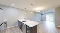 Located at 5510 Southwestern Blvd in Hamburg, NY, this well-appointed single-floor residence offers 2 bedrooms and 3 bathrooms with a thoughtfully designed open-concept layout. The kitchen is a standout feature, showcasing dark cabinetry, white quartz countertops, stainless steel appliances including a refrigerator, gas range, microwave, and dishwasher, as well as a large center island with an undermount sink and matte black faucet. Pendant lighting overhead adds a modern touch, while light hardwood-style flooring flows throughout the main living areas. The living room offers a bright, open feel with recessed lighting and a sliding glass door that fills the space with natural light and provides outdoor views. The spacious primary bedroom features plush carpeting, a ceiling fan, and a generously sized window. The second bedroom is equally comfortable with carpet flooring and natural light from a large window. Three well-finished bathrooms feature wood-look tile flooring, dark vanity cabinetry, white countertops, and matte black hardware accents. A dedicated laundry room accommodates a full-size washer and dryer with built-in shelving overhead. Clean grey tones and contemporary finishes throughout create a cohesive, modern aesthetic.
