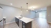 Located at 5510 Southwestern Blvd in Hamburg, NY, this well-appointed single-floor residence offers 2 bedrooms and 3 bathrooms with a thoughtfully designed open-concept layout. The kitchen is a standout feature, showcasing dark cabinetry, white quartz countertops, stainless steel appliances including a refrigerator, gas range, microwave, and dishwasher, as well as a large center island with an undermount sink and matte black faucet. Pendant lighting overhead adds a modern touch, while light hardwood-style flooring flows throughout the main living areas. The living room offers a bright, open feel with recessed lighting and a sliding glass door that fills the space with natural light and provides outdoor views. The spacious primary bedroom features plush carpeting, a ceiling fan, and a generously sized window. The second bedroom is equally comfortable with carpet flooring and natural light from a large window. Three well-finished bathrooms feature wood-look tile flooring, dark vanity cabinetry, white countertops, and matte black hardware accents. A dedicated laundry room accommodates a full-size washer and dryer with built-in shelving overhead. Clean grey tones and contemporary finishes throughout create a cohesive, modern aesthetic.