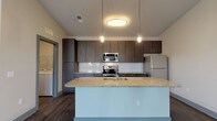 This well-appointed single-floor residence offers a thoughtfully designed layout with contemporary finishes throughout. The open-concept kitchen serves as the heart of the home, showcasing rich dark wood cabinetry, granite countertops, and a large central island with an integrated sink — ideal for both meal preparation and casual dining. A full suite of stainless steel appliances, including a range, over-the-range microwave, and refrigerator, is complemented by a classic white subway tile backsplash and warm hardwood-style flooring. Pendant and flush-mount lighting add a polished touch overhead.

The bedrooms are finished with plush carpeting, neutral-toned walls, and ceiling fans, offering a comfortable and restful atmosphere. Multiple windows fitted with blinds allow natural light to filter in while maintaining privacy. Additional carpeted spaces provide flexible use for storage or other needs.

The bathroom features granite countertops atop dark cabinetry, a single undermount sink, wood-style flooring, and a glass-enclosed shower with chrome fixtures and grab bars. A dedicated laundry area includes a full-size washer and dryer with overhead wire shelving for added storage. Together, these elements create a cohesive, modern living environment with practical, high-quality amenities throughout.