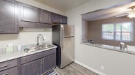 Located at 526 Carl St in Gastonia, NC, this single-floor unit offers a well-designed, functional layout with modern updates throughout. The kitchen is a standout feature, equipped with dark espresso-toned shaker-style cabinetry, granite-look countertops, and a full suite of stainless steel appliances including a gas range, refrigerator, and double-basin sink with a pull-down faucet. An open pass-through window connects the kitchen to the adjacent living and dining area, creating a cohesive, open feel ideal for everyday living and entertaining. The living area is generously sized, featuring durable wood-look flooring, neutral-toned walls, a ceiling fan with light fixture, and a window that brings in natural light. A dedicated bedroom provides a comfortable retreat, also finished with wood-look flooring, a window with blinds, and a textured ceiling with flush-mount lighting. The bathroom is cleanly appointed with a granite-look vanity countertop, an integrated sink, a large mirror, and bright overhead lighting. Consistent flooring and neutral tones flow throughout the space, creating a cohesive and move-in-ready environment.