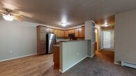 Located at 1711 Cottontail Ln in Reedsburg, Wisconsin, this single-floor unit offers a functional and practical layout designed for comfortable everyday living. The kitchen serves as a central feature of the space, outfitted with warm honey-toned wood cabinetry extending to the ceiling, dark granite-style countertops, and a full suite of stainless steel appliances including a refrigerator, range, microwave, and dishwasher. Durable wood-look flooring runs throughout the kitchen, while a peninsula with a breakfast bar provides a natural transition into the adjacent living area. The living room is generously sized, featuring neutral carpet, baseboard heating, and access to natural light through a sliding door with vertical blinds.

The bedroom is well-proportioned, carpeted, and includes a ceiling fan with light fixture and a window for natural light. Two bathrooms serve the unit — one featuring a walk-in shower stall, wood-toned cabinetry with granite-style counters, and wood-look flooring, while the second offers similar finishes with additional wall-mounted storage. A hallway connects the private areas of the unit efficiently. The attached garage provides enclosed parking and additional storage space with an automatic opener.