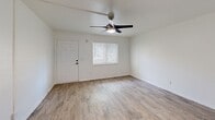 Located at 3531 Plantation Way in Naples, FL, this one-bedroom, one-bathroom unit offers a compact yet efficiently organized single-floor layout. The interior is finished with light wood-look plank flooring throughout the main living areas, contributing to a clean, cohesive aesthetic.

The living room is bright and open, featuring white walls, a ceiling fan with integrated lighting, and a window fitted with blinds that allows natural light to filter in. A front entry door with a modern hardware finish anchors the space. A sliding barn door serves as a functional design detail, dividing areas within the unit and adding a contemporary touch.

The bedroom features a bold dark accent wall contrasting with white walls on the remaining sides, creating visual interest. A wall-mounted mini-split HVAC unit provides climate control, accompanied by a ceiling fan. A sliding double-panel closet offers storage, and a window with blinds brings in additional natural light with views of outdoor greenery.

The bathroom is finished with light tile flooring and includes a combined shower and tub, a toilet, and a vanity with dark cabinetry. The layout is straightforward and functional. A kitchenette area visible in the floor plan scan includes a sink and shelving. Overall, the unit presents a practical, updated interior suitable for efficient single-occupant living.