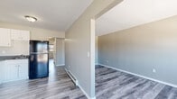 Located at 2201 Vails Gate Heights Dr in New Windsor, NY, this one-bedroom, one-bathroom residence offers a thoughtfully organized single-floor layout that makes efficient use of its space. Gray vinyl plank flooring runs throughout, providing a clean, cohesive look that ties each room together.

The open-concept kitchen and living area forms the heart of the home. The kitchen features white shaker-style cabinetry with brushed nickel hardware, dark countertops, and black appliances including a refrigerator, electric range, and built-in microwave. The adjacent living room is bright and airy, with large windows fitted with a wall unit for climate control and a baseboard heating system beneath. A sliding glass door leads to a private balcony overlooking the surrounding neighborhood.

The spacious primary bedroom offers generous proportions, a large window with outdoor views, and consistent flooring carried throughout. A connecting hallway provides access to the full bathroom, which is finished with white subway tile in the tub surround, white tile flooring, a gray vanity with gold-toned fixtures, and a medicine cabinet mirror. The overall palette of neutral grays and whites creates a clean, move-in-ready aesthetic throughout the home.
