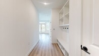 This well-designed single-story home offers 2 bedrooms and 2 bathrooms within a thoughtfully laid-out floor plan. Light wood-tone flooring runs consistently throughout the space, creating a cohesive and clean aesthetic complemented by crisp white walls and black hardware accents.

The entry hallway serves as a functional mudroom, featuring built-in shelving, lower cubbies, and wall-mounted coat hooks — an organized and practical welcome space. The hallway leads naturally into the open kitchen and living area. The kitchen is equipped with slate-gray shaker cabinetry, a granite peninsula countertop, a white tile backsplash, stainless steel appliances, and a window above the sink for natural light. The adjacent living room is bright and airy, with large windows and a glass door that invite ample outdoor light and offer exterior views, along with a ceiling fan overhead.

Both bedrooms are generously sized with ceiling fans, large windows, and direct access to closet space. The primary bedroom includes an en-suite bathroom and a walk-in closet with built-in shelving. The second bedroom also benefits from natural light and its own closet with louvered doors. Two full bathrooms serve the home, with clean, modern finishes visible throughout. A central hallway connects all rooms efficiently, completing this well-organized and move-in ready layout.