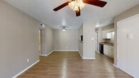 This single-floor, 3-bedroom, 2-bathroom residence offers a practical and comfortable layout designed to maximize functionality. The open-concept living and kitchen area serves as the heart of the home, featuring warm wood-look laminate flooring, neutral taupe walls, and a textured ceiling. A ceiling fan with light fixture keeps the space comfortable, while sliding glass doors with vertical blinds provide access to an outdoor area and bring in natural light. The kitchen is equipped with white cabinetry, granite-look countertops, a stainless steel refrigerator, a black dishwasher, and a sink, offering efficient use of space.

The three bedrooms are each finished with the same wood-look flooring, neutral walls, and ceiling fans. Natural light filters in through blinded windows, with views of the surrounding exterior. The primary bedroom provides a generous amount of floor space. Both bathrooms feature wood-look tile flooring, vanities with granite-look countertops, large mirrors with overhead lighting, and a shower-tub combination with white tile surround. A hallway connects the bedrooms and bathrooms, and a dedicated closet provides additional storage. The consistent finishes throughout create a cohesive and clean aesthetic across the entire unit.