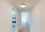 Located in Miami, FL, this single-floor residence offers a clean, bright, and efficiently laid-out living environment. Light-colored ceramic tile flooring runs consistently throughout the entire space, lending a cohesive and easy-to-maintain aesthetic.

Upon entry, a welcoming foyer with a solid front door leads into the main living areas. The spacious living room is bathed in natural light from a large window fitted with vertical blinds, offering views of lush greenery outside. A ceiling fan adds comfort to the room's airy atmosphere.

The kitchen is well-equipped, featuring white raised-panel cabinetry that extends to the ceiling for generous storage, granite countertops, a stainless steel sink, and white appliances including a refrigerator, dishwasher, stove, oven, and an over-the-range microwave. Track lighting illuminates the workspace effectively.

A hallway connects the living areas to the bedrooms. Each bedroom is comfortably sized with white walls, tile flooring, and closets with louvered bifold doors. The bathroom is neatly appointed with recessed lighting, a tiled shower-tub combination with glass sliding doors, and granite countertop details that echo the kitchen's finishes.

Overall, the space presents a bright, functional, and well-maintained interior well-suited for comfortable South Florida living.