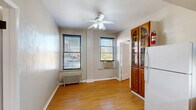 Located at 12 S Mill St in Pontiac, Michigan, this 2-bedroom, 2-bathroom unit offers a practical and efficiently designed single-floor layout. Wood-look flooring runs throughout the space, lending warmth and visual continuity across all rooms.

The combined living, dining, and kitchen area serves as the heart of the unit. The living and dining space features a ceiling fan with light fixture, two windows fitted with blinds that allow natural light to filter in, and a classic cast-iron radiator for heating. A wall-mounted air conditioning unit provides additional climate control. A charming tall wooden display cabinet with arched glass doors adds a decorative touch near the kitchen entry.

The kitchen is compact yet functional, outfitted with warm wood cabinetry, tile backsplash, white laminate countertops, a stainless steel sink, and white appliances including a full-size refrigerator and microwave. Two closets provide dedicated storage throughout the unit.

The primary bedroom accommodates a comfortable layout with multiple windows offering natural light and a radiator. The second bedroom includes a drop ceiling, wood-paneled walls, and access to a closet. Each bathroom has its own distinct character — one features a full tub/shower combo with a pedestal sink, while the second is a compact water closet with a wall-mount sink. A hallway connects the rooms, completing this efficiently organized unit.