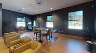 Located in the Rancho Peñasquitos neighborhood of San Diego, this single-floor amenity space serves as a vibrant entertainment and lounge area designed for recreation and social gathering. The interior is defined by eye-catching textured wallcoverings in deep navy and slate blue tones, paired with warm light wood flooring that runs throughout, creating a contemporary yet inviting atmosphere.

The space is thoughtfully divided into distinct activity zones. A dedicated gaming area features a classic Star Wars pinball machine, a tabletop arcade game, and a full-size pinball cabinet, offering a curated selection of entertainment options. Multiple flat-screen televisions are mounted on wood media consoles, accompanied by comfortable lounge chairs and swivel seating for viewing and relaxation.

High-top tables with bar-height chairs provide casual seating throughout, ideal for group gatherings or individual use. Natural light filters in through several windows, offering views of the surrounding landscaping and neighborhood, while recessed ceiling lighting ensures a well-lit environment at all times.

Decorative framed wall art, including large-scale nature-inspired prints, adds a refined touch to the space. Subtle greenery, including a potted indoor palm, contributes to the overall warmth of the design. The open, well-organized layout accommodates a variety of activities, making this a versatile and engaging communal destination.