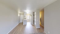 This single-story unit located on 16th Street West in Lancaster, California, offers a straightforward and functional layout designed for comfortable everyday living. The open-concept living and dining area features a combination of light wood-style hard flooring and plush carpet, creating a natural visual distinction between zones. A sliding glass door allows natural light to filter into the living space while providing outdoor access.

The kitchen is designed with white cabinetry extending to the ceiling, white appliances including a gas range and full-size refrigerator, and a light-toned countertop with a breakfast bar overhang. A built-in shelving unit adjacent to the kitchen offers additional storage and display space. The kitchen benefits from a window that brings in natural light.

The bedrooms are carpeted and finished in neutral tones, each featuring windows with vertical blinds and textured ceilings. At least one bedroom includes a built-in closet with shelving for organized storage. The bathroom is equipped with a full tub and shower combination featuring a grab bar, a toilet, and a single-sink vanity with a speckled countertop and white cabinetry, complemented by wood-style flooring.