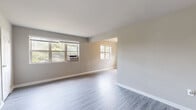 Located at 3512 54th Ave in Hyattsville, Maryland, this single-floor residence offers a clean, updated interior with a neutral color palette and thoughtful finishes throughout. The open living area is anchored by light-toned luxury vinyl plank flooring that reflects natural light streaming in through multiple windows, creating a bright and airy atmosphere. A window air conditioning unit serves the main living space, while the open layout allows for flexible furniture arrangements.

The kitchen is well-appointed with rich dark wood cabinetry, granite countertops, a stainless steel gas range, and a full-size stainless steel refrigerator, providing a functional and stylish cooking environment. An additional room with matching LVP flooring and dual windows offers versatility as a dining area or flex space.

The bedrooms feature plush carpeting, ceiling fans, and windows with views of surrounding greenery, lending a comfortable and private feel to each room. One bedroom includes dual windows with a window AC unit for independent climate control.

The bathroom is finished with light LVP flooring, a dark-cabinet vanity with a white sink, a lighted mirror, and a tiled shower-tub combination, complemented by a window for natural ventilation. Clean white trim and neutral gray walls unify the aesthetic across the entire residence.