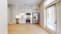 Located in Decatur, GA, this efficiently designed single-floor unit offers a thoughtful layout with a fully equipped kitchen and two bathrooms. The kitchen is a standout feature, showcasing floor-to-ceiling white shaker cabinetry, a classic white subway tile backsplash, and a full suite of stainless steel appliances including a French door refrigerator with ice and water dispenser, a gas range, built-in microwave, and dishwasher. Light hardwood-style flooring runs throughout the main living area, enhancing the bright, airy atmosphere. A glass-paneled exterior door allows natural light to pour in and offers views of the surrounding neighborhood. The bathrooms are elegantly appointed with white quartz countertops, undermount sinks, and matte black hardware accents. The primary bathroom is a particular highlight, featuring floor-to-ceiling marble-look porcelain tile, a glass-enclosed walk-in shower with a mosaic tile floor and rain showerhead, and matching marble-style flooring. Panel-molded doors and a double closet add functional storage. The clean, neutral palette and modern finishes throughout create a cohesive and sophisticated ambiance suited for contemporary living.