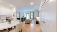 This well-appointed 3-bedroom, 2-bathroom residence in Indian Land, SC offers a thoughtfully designed single-level layout that maximizes functionality and comfort. The open-concept kitchen and living area serves as the heart of the home, featuring crisp white shaker cabinetry, granite countertops, a full suite of stainless steel appliances, and light hardwood flooring that extends throughout the main living spaces. A dedicated dining area with a round marble-top table sits adjacent to the kitchen, making it ideal for everyday meals and entertaining. The living room is bright and welcoming, with large windows dressed in neutral drape panels that invite natural light, and a glass door providing access to the outdoors. Each bedroom is finished with plush carpeting and ceiling fans, with the primary bedroom benefiting from a dedicated walk-in closet. Both bathrooms are outfitted with white shaker vanities, granite countertops, and hardwood-style flooring. A secondary bedroom includes a double-door closet, adding practical storage. The clean, neutral color palette and consistent finishes throughout create a cohesive and modern ambiance, making this residence a comfortable and move-in-ready home in the Jessamine Grove community.