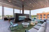 Located in Atlanta's 30316 zip code, this single-floor amenity space is designed as a dynamic, social hub with a variety of recreational and lounge areas. The interior opens with soaring double-height ceilings that amplify the sense of openness, while expansive floor-to-ceiling windows flood the space with natural light and frame sweeping views of the surrounding Atlanta skyline and treetops.

The main gathering area features wood-look luxury vinyl flooring throughout and is anchored by a stylish wet bar clad in bold black-and-white herringbone tile, topped with a light countertop and surrounded by red-cushioned bar stools. Elegant pendant lighting hangs above, complementing the double-height glazing behind.

Adjacent to the bar, a dedicated game room offers a rustic billiards table with a red felt surface, arcade machines, a shuffleboard table, and casual seating arrangements with round tables and woven chairs — ideal for social entertainment.

A hallway with clean white walls, wood-look flooring, and vintage-style artwork leads to restroom facilities. French doors open onto a spacious outdoor rooftop terrace featuring large-format tile flooring, a wood-paneled ceiling, glass railings, built-in planter boxes, and a mix of bar-height seating and lounge chairs — all set against open Atlanta skyline views.