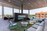 Located in Atlanta's 30316 zip code, this single-floor amenity space is designed as a dynamic, social hub with a variety of recreational and lounge areas. The interior opens with soaring double-height ceilings that amplify the sense of openness, while expansive floor-to-ceiling windows flood the space with natural light and frame sweeping views of the surrounding Atlanta skyline and treetops.

The main gathering area features wood-look luxury vinyl flooring throughout and is anchored by a stylish wet bar clad in bold black-and-white herringbone tile, topped with a light countertop and surrounded by red-cushioned bar stools. Elegant pendant lighting hangs above, complementing the double-height glazing behind.

Adjacent to the bar, a dedicated game room offers a rustic billiards table with a red felt surface, arcade machines, a shuffleboard table, and casual seating arrangements with round tables and woven chairs — ideal for social entertainment.

A hallway with clean white walls, wood-look flooring, and vintage-style artwork leads to restroom facilities. French doors open onto a spacious outdoor rooftop terrace featuring large-format tile flooring, a wood-paneled ceiling, glass railings, built-in planter boxes, and a mix of bar-height seating and lounge chairs — all set against open Atlanta skyline views.