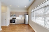 Located at 6276 Newton Rd in Haslett, Michigan, this one-bedroom, one-bathroom unit offers a thoughtfully designed single-floor layout that maximizes every square foot. The kitchen is a standout feature, showcasing stainless steel appliances including a range, over-the-range microwave, dishwasher, and refrigerator. Light taupe shaker-style cabinetry pairs elegantly with white countertops and a classic white subway tile backsplash, creating a clean and modern aesthetic. Warm hardwood-style flooring runs throughout the kitchen and living areas, complemented by recessed lighting and a large window that invites natural light into the space. The bedroom is carpeted for comfort and features a built-in closet with wire shelving, offering organized storage. Neutral gray walls throughout provide a calm, versatile backdrop. The bathroom is well-appointed with a single vanity topped with a light countertop, a large mirror, a tub-shower combination, and hardwood-style flooring that carries through from the main living areas. Clean white trim and brushed nickel fixtures add a cohesive, contemporary touch throughout. The overall ambiance is bright, fresh, and move-in ready, making it a practical and comfortable living space.