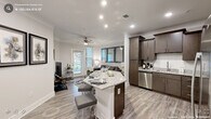 This one-bedroom, one-bathroom residence on Watchorn Street in Durham, NC, offers a thoughtfully designed single-level layout that maximizes functionality and style. The open-concept kitchen and living area forms the heart of the unit, where rich dark-brown cabinetry reaches toward the ceiling, complemented by granite countertops, a full suite of stainless steel appliances, and a peninsula island with bar seating — ideal for casual dining or entertaining. Light wood-tone flooring runs throughout the main living areas, enhancing the bright, neutral color palette.

The living room is generously proportioned, featuring crown molding, a ceiling fan, and multiple windows with natural light and outdoor views. A private entry door provides direct exterior access from this space.

The bedroom is a comfortable retreat with plush carpeting, a ceiling fan, and ample room for a full furniture arrangement. A dedicated closet provides organized storage, and the adjoining hallway connects to the full bathroom.

The bathroom is well-finished, offering a granite-topped vanity with dark cabinetry, a tub-shower combination, tile flooring, and a large mirror above the sink. Throughout the unit, recessed lighting and crown molding details contribute to a polished, cohesive aesthetic.