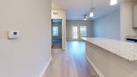 Located at Avida Village Circle in Orlando, FL, this one-bedroom, one-bathroom residence offers a thoughtfully designed single-floor layout with a clean, contemporary aesthetic throughout. Light wood-style flooring runs through the main living areas, complementing the soft gray walls and bright white baseboards that give the space a fresh, modern feel.

The kitchen is a standout feature, offering an abundance of gray shaker-style cabinetry, granite countertops, a subway tile backsplash, and a full suite of stainless steel appliances including a refrigerator with ice maker, electric range, built-in microwave, and dishwasher. A spacious island with additional storage and a pendant light adds both function and style.

The open living area connects seamlessly to the kitchen and features a ceiling fan with a pendant-style light fixture, and glass doors that allow natural light to fill the space. The bedroom is a comfortable, well-proportioned room with plush carpeting, a ceiling fan, a window with exterior views, and a dedicated closet. The bathroom includes a full tub and shower combination with white subway tile surround. A dedicated laundry room houses a full-size Whirlpool washer and dryer with overhead wire shelving for added storage convenience.
