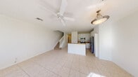 This two-story home is designed with a clean, open layout that maximizes both functionality and natural light throughout. The main level welcomes you through an entry hallway that opens into a generous living and dining area, finished with light-toned ceramic tile flooring and a ceiling fan overhead. Large windows at the rear of the home flood the space with natural light and offer views of the outdoors.

The kitchen is thoughtfully designed with white cabinetry, granite-look countertops, a central island with pendant lighting, and stainless steel appliances including a built-in microwave, electric range, and French door refrigerator. A staircase with a classic white balustrade connects the main floor to the upper level.

Upstairs, carpeted bedrooms provide a comfortable retreat. The primary bedroom is generously proportioned, featuring a ceiling fan, a large window with outdoor views, and access to a walk-in closet with built-in shelving. The en suite bathroom includes a soaking tub with tile surround, a vanity with ample counter space, and tile flooring. Additional bedrooms are well-sized with natural light and access to a full bathroom featuring a tub-shower combo and white vanity. A carpeted upper hallway with an open railing overlooks the lower level, adding an airy, connected feel to the home.
