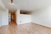 Located at 4455 35th Ave SW in Seattle's West Seattle neighborhood, this well-designed one-bedroom, one-bathroom unit offers a thoughtful layout across a single floor. Light wood-style flooring runs throughout, lending a clean, cohesive aesthetic to every room.

The open combined living and dining area is generously proportioned, featuring crisp white walls, recessed lighting, and large windows that frame lush tree views and fill the space with natural light. The kitchen is outfitted with white shaker-style cabinetry, dark countertops, a textured tile backsplash, and a full suite of stainless steel appliances including a refrigerator, range, and over-the-range microwave.

A hallway connects the main living areas to the private bedroom, which benefits from its own large window overlooking greenery. The unit also includes a dedicated den, offering flexible space for a home office or additional living area. Four closets provide ample storage throughout.

The full bathroom features a soaking tub with shower, a white vanity with dark countertop, and consistent wood-style flooring. A dedicated laundry room houses a stacked Whirlpool washer and dryer. The entrance area completes this well-organized and functional unit.