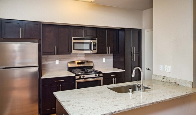 Cocina moderna con electrodomésticos de acero inoxidable, encimeras de granito y gabinetes de primera calidad. - Monterey Grove