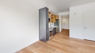Located in Salt Lake City, UT 84111, this efficiently designed studio/one-bedroom unit offers a thoughtfully laid-out single-floor living space. Light-toned hardwood flooring runs throughout, lending warmth and cohesion to the entire unit.

The open living area is bright and airy, anchored by a large window and glass door that frame views of surrounding trees and the city skyline, with a ceiling fan providing comfort overhead. The clean white walls and abundant natural light create an inviting, open atmosphere.

The kitchen is a standout feature, combining functionality with modern style. It showcases a mix of warm wood upper cabinetry and sleek dark lower cabinets and tall storage tower, complemented by stainless steel appliances including a range and dishwasher. A subway tile backsplash adds a clean, contemporary finish.

The bathroom is finished with a crisp, all-white aesthetic, featuring a full glass-enclosed walk-in shower lined with white subway tile, matte black hardware accents, and wood-tone flooring that carries through from the main living areas.

Additional features include recessed lighting, clean white interior doors with modern hardware, and a straightforward, efficient layout that maximizes the use of the available space. This unit is ideal for those seeking a contemporary, low-maintenance living environment in the heart of Salt Lake City.