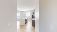Located at 1418 Carroll St in St. Louis, MO, this thoughtfully designed single-floor residence blends modern finishes with functional living spaces. The open-concept kitchen serves as the heart of the home, showcasing a large center island with a white quartz countertop, undermount sink, and stylish pendant lighting. Two-tone cabinetry in dark gray and white pairs with a textured tile backsplash, while stainless steel appliances — including a refrigerator, range, and microwave — complete the contemporary aesthetic. Large windows flood the kitchen and adjoining living area with abundant natural light.

Light-toned hardwood flooring extends throughout the main living areas, contributing to a bright and airy atmosphere. The living space is generously proportioned with high ceilings and clean white walls, offering a versatile canvas for various furniture arrangements. Bedrooms feature plush carpeting, multiple windows for natural light, and ample space, with one room showcasing an exposed white brick wall that adds a distinctive industrial character. A sliding barn-style door provides a stylish transition between spaces. The overall design is clean, modern, and move-in ready.