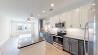 Located at 905 Lakeford Dr in Morrisville, NC, this well-appointed one-bedroom, one-bathroom residence offers a thoughtfully designed single-floor layout with a clean, contemporary aesthetic throughout. Light-toned hardwood-style flooring flows seamlessly across every room, complemented by crisp white walls and generous natural light.

The open-concept kitchen, dining, and living area serves as the heart of the home. The kitchen is a standout, featuring two-tone cabinetry — white upper shaker-style cabinets paired with slate-gray lower cabinets — topped with sleek countertops. A herringbone-patterned tile backsplash adds visual texture, while a center island provides additional prep space and seating. A full suite of stainless steel appliances, including a refrigerator, range, microwave, and dishwasher, completes the space. Pendant lighting over the island and recessed ceiling lights enhance both function and style. A glass-panel door off the living area provides access to an outdoor balcony.

The bedroom is comfortably sized, featuring a ceiling fan, a large window with exterior views, and direct access to a spacious walk-in closet outfitted with built-in shelving and hanging rods. The bathroom and additional utility areas round out this efficiently planned residence.