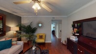 Located at 11655 Briar Forest Dr in Houston, Texas, this single-floor residence offers a well-planned layout with thoughtfully designed living spaces throughout. The living room serves as the heart of the home, showcasing rich hardwood flooring, crown molding, and a ceiling fan with light fixture. The space is anchored by a comfortable seating arrangement set against a bold accent wall, complemented by warm ambient lighting and lush indoor greenery that adds a welcoming, vibrant character.

The dining area flows naturally from the living space, featuring the same hardwood flooring and crown molding detail, with a console table and mirror adding decorative depth. The galley-style kitchen is efficiently organized with light wood cabinetry, dark countertops, tile flooring, and full black appliance suite including a range and refrigerator.

The bedroom offers plush carpeting, a ceiling fan, a striking navy accent wall, and a generous window that allows natural light to filter in. Two bathrooms serve the home — one featuring a tub/shower combination with dark granite-style countertops and a well-lit vanity mirror, and a second more compact bath with similar finishes. A dedicated in-unit laundry area with side-by-side washer and dryer and built-in shelving adds practical convenience to this functional Houston residence.