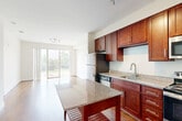 Located at 9142 Richmond Hwy in Fort Belvoir, Virginia, this one-bedroom, one-bathroom residence offers a thoughtfully designed single-level layout. The open-concept kitchen and living area serves as the heart of the home, where rich cherry wood cabinetry, granite countertops, and a full suite of stainless steel appliances — including a refrigerator, range, microwave, and dishwasher — create a polished and functional culinary space. A freestanding kitchen island with a granite top provides additional prep and dining space. Warm hardwood flooring flows throughout the main living areas, complemented by abundant natural light and track lighting overhead. Sliding glass doors open to a private balcony overlooking lush greenery, seamlessly blending indoor and outdoor living. The generously sized bedroom features plush carpeting, a ceiling fan, and a large window framing serene outdoor views. The bathroom is finished with matching granite countertops, rich cabinetry, and a tiled shower-tub combination. Additional conveniences include three closets, in-unit laundry, a utility room, and a hallway connecting the thoughtfully arranged spaces. The overall ambiance is clean, modern, and move-in ready.