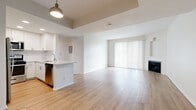 Located at 11615 Firestone Blvd in Norwalk, CA, this well-designed 2-bedroom, 2-bathroom residence offers a thoughtful single-floor layout that maximizes functionality and comfort. The open-concept living and kitchen area serves as the heart of the home, featuring light wood-style flooring that runs throughout the entire unit, lending a clean and cohesive feel. The living room is bright and airy, highlighted by large sliding glass doors with vertical blinds that invite natural light, and a sleek fireplace that adds warmth and character to the space. The kitchen is outfitted with stainless steel appliances — including a refrigerator, gas range, and microwave — paired with crisp white cabinetry, a light countertop peninsula with an integrated sink, recessed lighting, and a pendant light fixture above. Both bedrooms are well-proportioned and filled with natural light; the second bedroom features dual corner windows. The primary bedroom connects to a dedicated walk-in closet with built-in shelving and hanging rods, offering generous storage. The bathroom features a white vanity with a quartz-style countertop, a single undermount sink with gold-tone fixtures, and a full shower-tub combination, all finished in a clean, contemporary style.