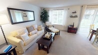 Located at 13011 Meridian E in Puyallup, Washington, this single-floor residence offers a thoughtfully designed layout with comfortable living spaces throughout. The living room serves as the heart of the home, featuring plush wall-to-wall carpeting, a large window that draws in abundant natural light, and neutral-toned walls that create a warm, inviting atmosphere. Decorative floating shelves add a functional yet stylish touch to the space.

The dining area is positioned adjacent to a full-height sliding glass door dressed with sheer vertical blinds, offering a seamless connection to the outdoors and filling the room with natural light. A ceiling fan with integrated lighting provides both comfort and ambiance in this space.

The bedroom is a calm retreat, appointed with soft carpeting, a sliding-door closet with built-in shelving for ample storage, and windows that allow gentle natural light to filter in. The textured ceilings are consistent throughout the home, adding a classic residential character.

The kitchen is efficiently designed, featuring light natural wood cabinetry, light-toned countertops, and a stainless steel sink — offering a clean and practical workspace. The overall layout of this residence is functional and cohesive, making it an ideal space for comfortable everyday living in the Puyallup community.